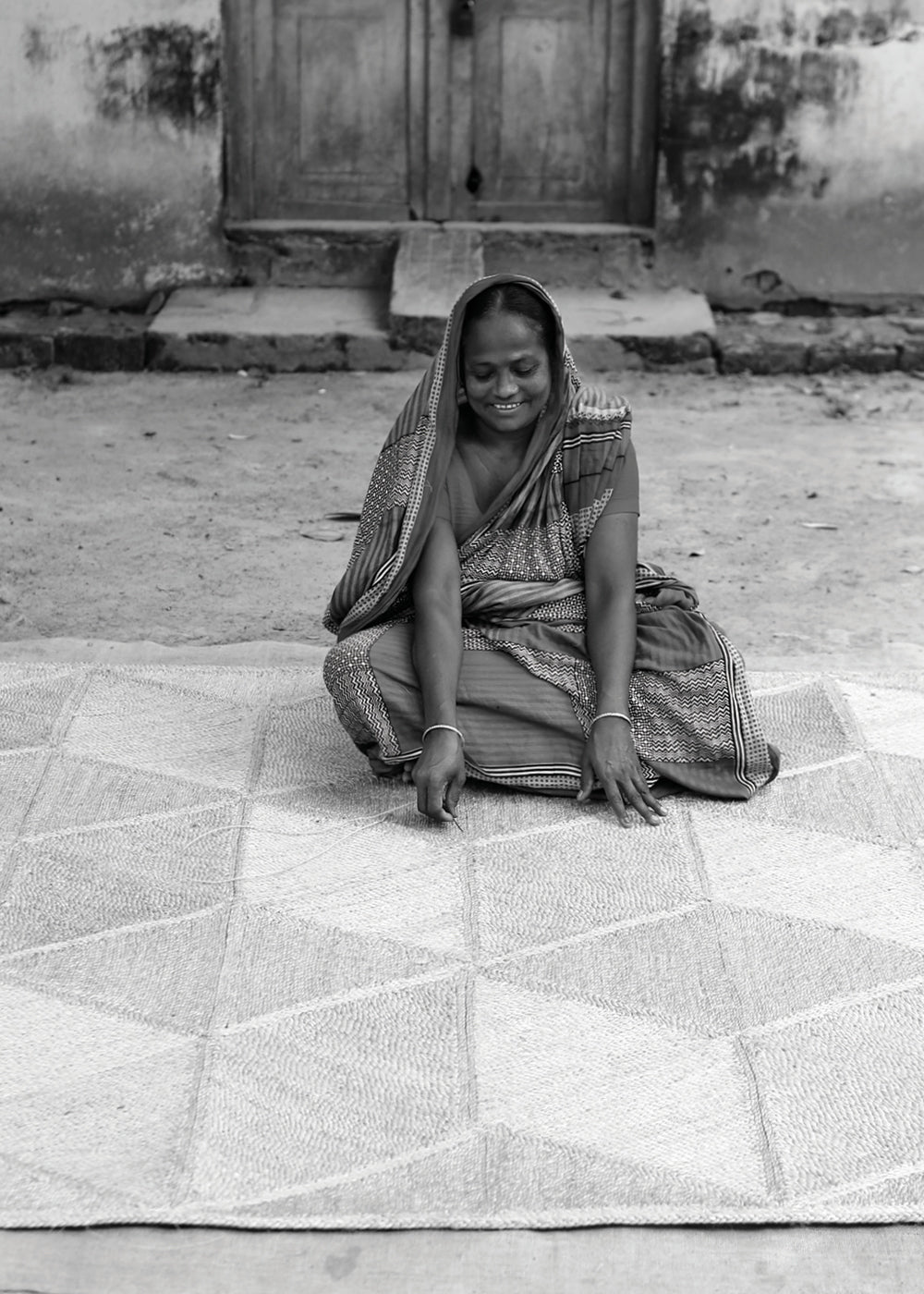 Fair trade artisans - Bangladeshi woman weaves natural jute carpet.