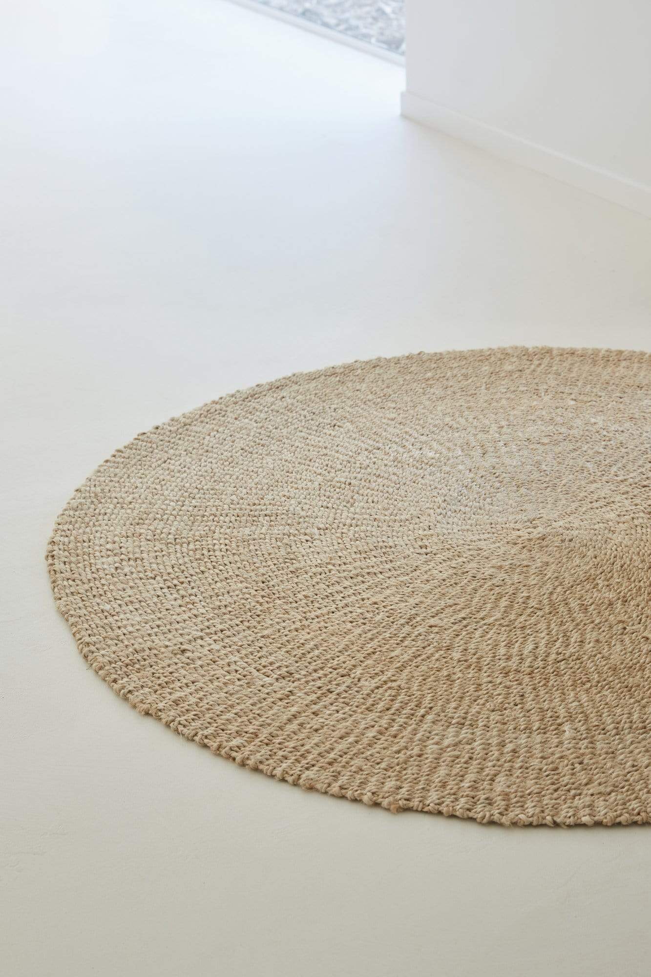 Large round woven natural jute rug in bedroom